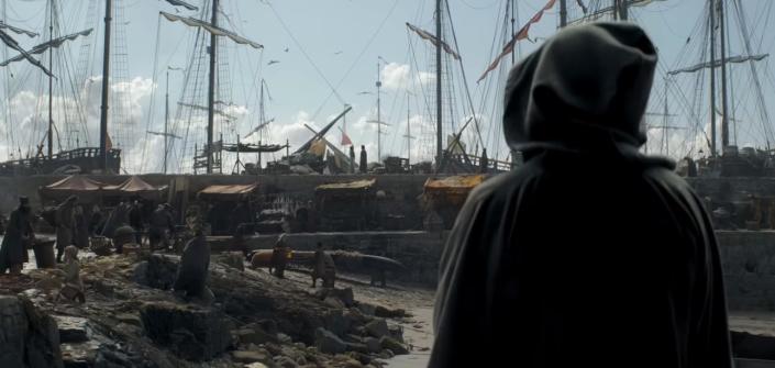 A hooded figure stares at boats docked and people milling about