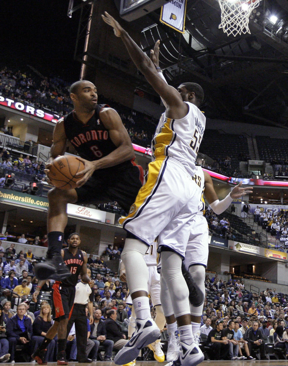 Toronto Raptors forward Alan Anderson, left, looks to pass around Indiana Pacers center Roy Hibbert in the first half of an NBA basketball game in Indianapolis, Monday, April 9, 2012. (AP Photo/Michael Conroy)