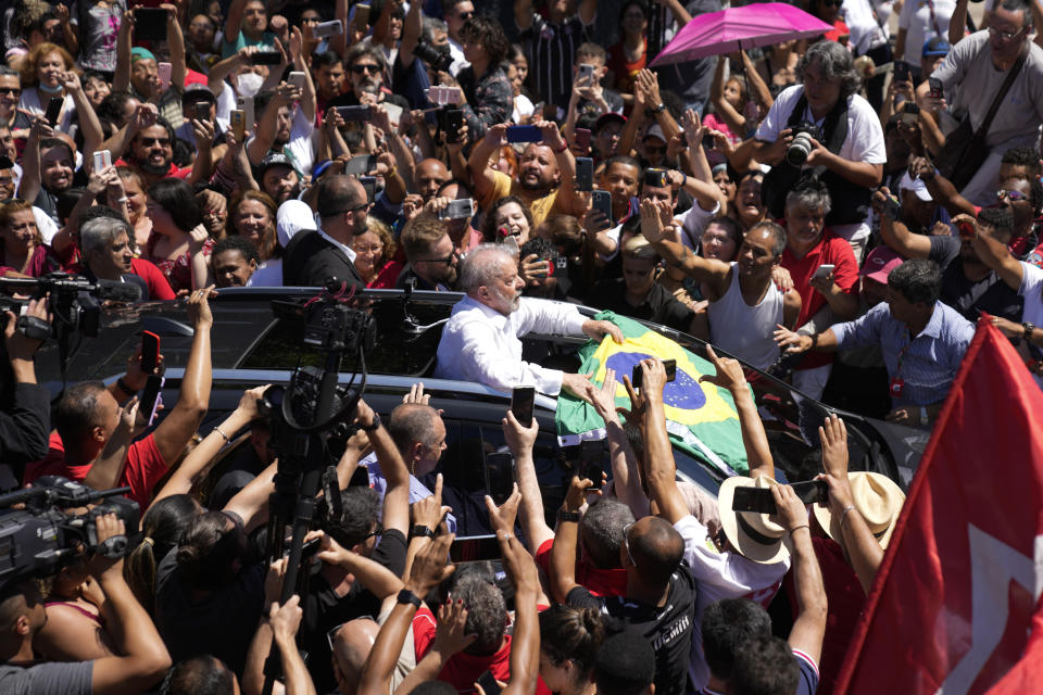 El expresidente Luiz Inácio Lula da Silva, al centro, sostiene una bandera de Brasil rodeado por simpatizantes tras depositar su voto en la segunda ronda electoral, el domingo 30 de octubre de 2022, en Sao Paulo, Brasil. (AP Foto/André Penner)