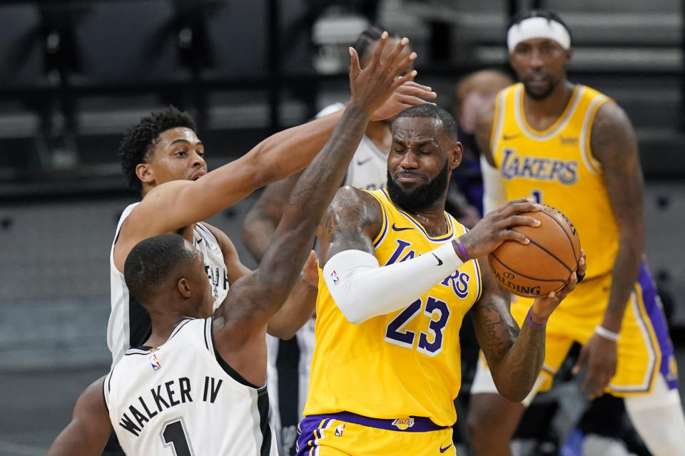 Los Angeles Lakers forward LeBron James (23) is pressured by San Antonio Spurs guard Lonnie Walker IV (1) and guard Keldon Johnson during the first half of an NBA basketball game in San Antonio, Wednesday, Dec. 30, 2020. (AP Photo/Eric Gay)