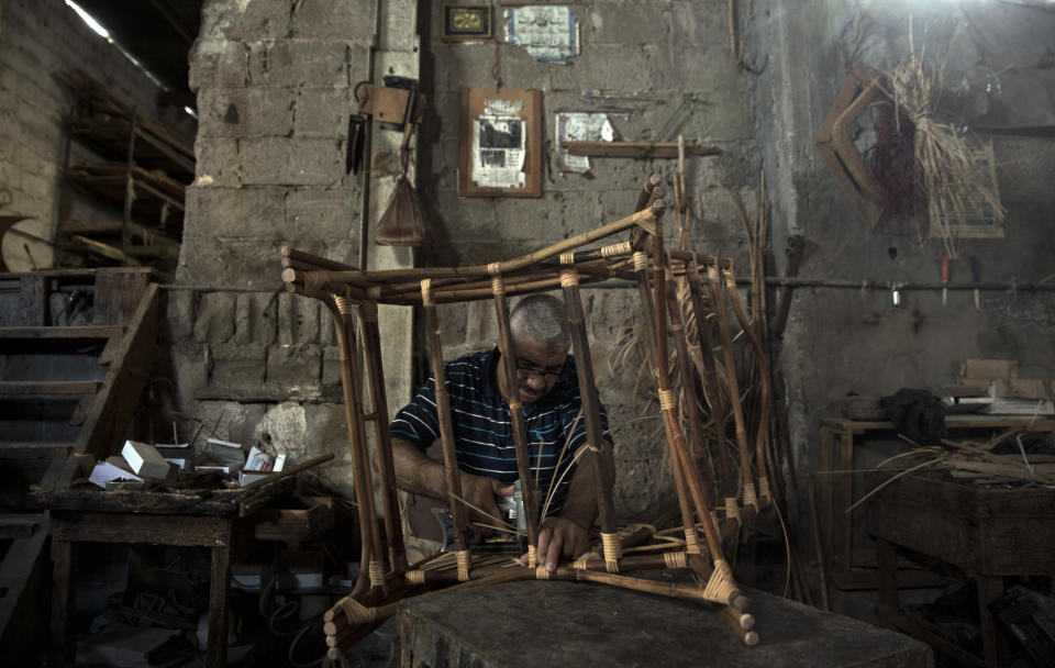 In this Saturday, July 6, 2019 photo, a Palestinian works at a bamboo workshop in Gaza City. Talk about old Gaza, and what pops up are images of clay pottery, colorful glassware, bamboo furniture and ancient frame looms weaving bright rugs and mats. As such professions could be dying worldwide, the pace of their declining is too fast in Gaza that out of its some 500 looms, only one is still functioning.(AP Photo/Khalil Hamra)