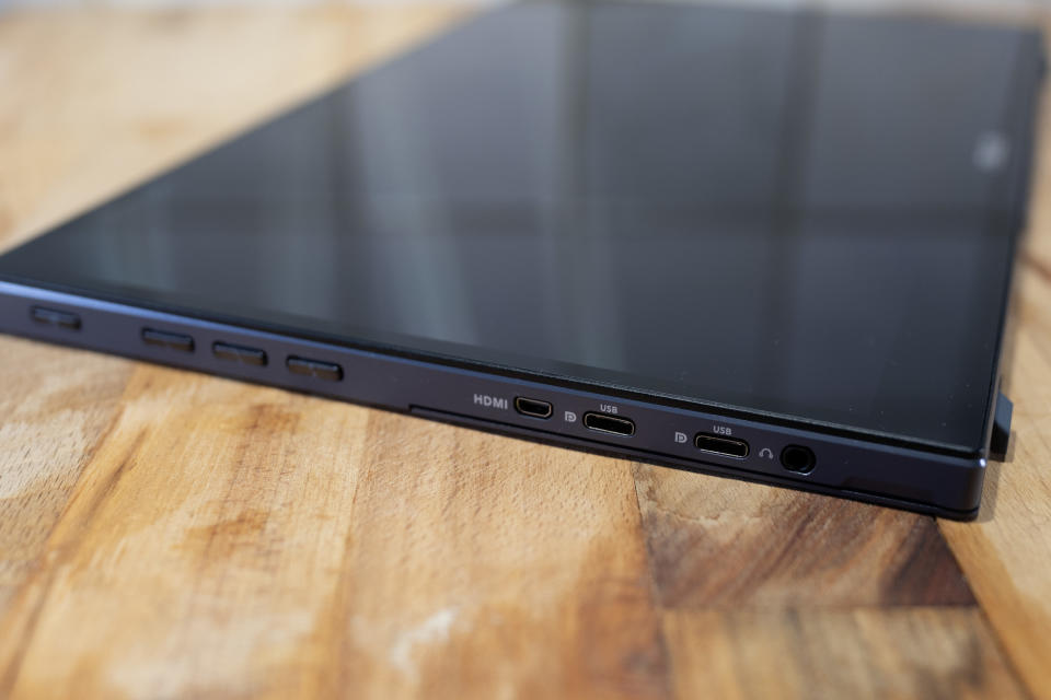 A black ASUS ZenScreen Ink MB14AHD monitor and accompanying stylus on a light wooden desk