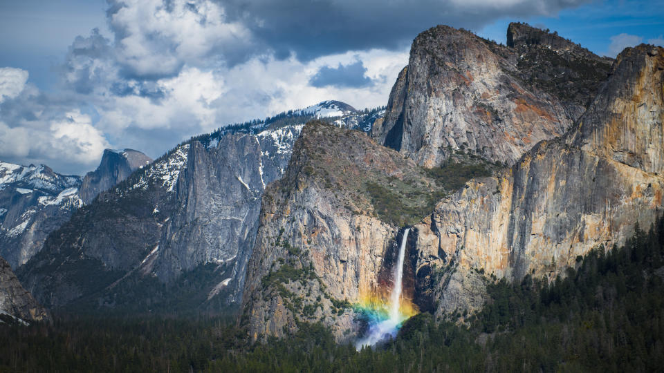 A rainbow emerges from the mist at the base of Bridal Veil Falls in California's Yosemite National Park