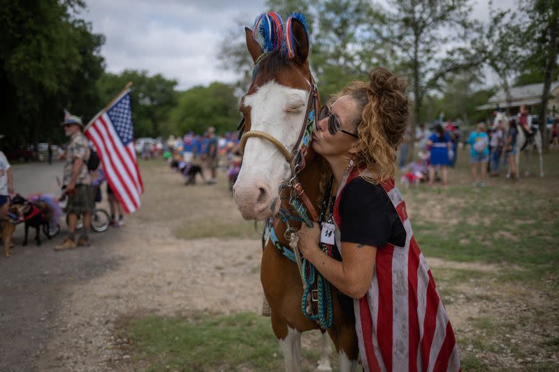 Una residente besa a un caballo antes del desfile de mascotas durante las celebraciones del Día de la Independencia en Bandera, Texas.