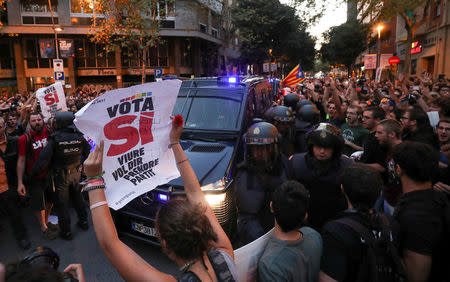 Protestors shout in front of a line of Spanish national police who surrounded the leftist Popular Unity Candidacy (CUP) party headquarters in Barcelona, Spain, September 20, 2017. REUTERS/Albert Gea