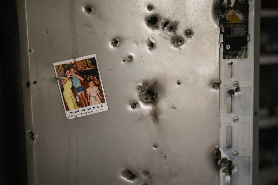 A photo hangs on a refrigerator riddled with bullet holes in a house at Kibbutz Kissufim in southern Israel, Saturday, Oct. 21, 2023. The Kibbutz was overrun by Hamas militants from the nearby Gaza Strip on Oct. 7, when they killed and captured many Israelis. (AP Photo/Francisco Seco)