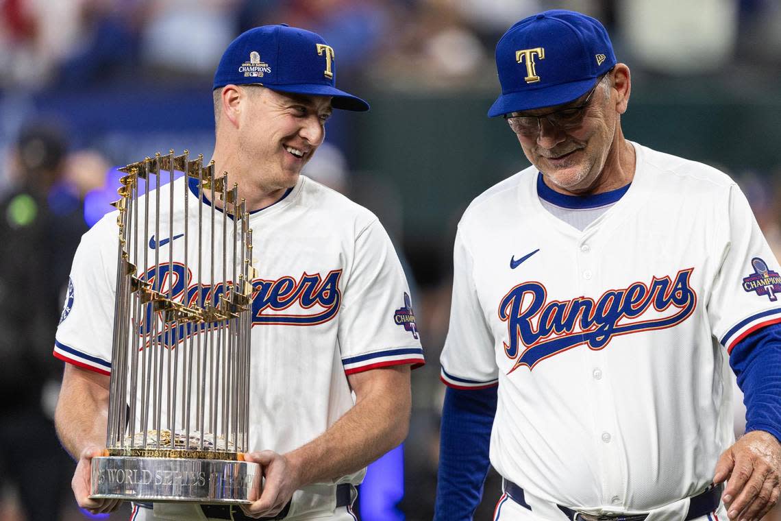 Rangers relief pitcher Josh Sborz and manager Bruce Bochy walk out to home plate with the World Series Commisioners Trophy for the World Series Banner ceremony prior to their season opener against the Chicago Cubs at Globe Life Field on Thursday, March 28, 2024.