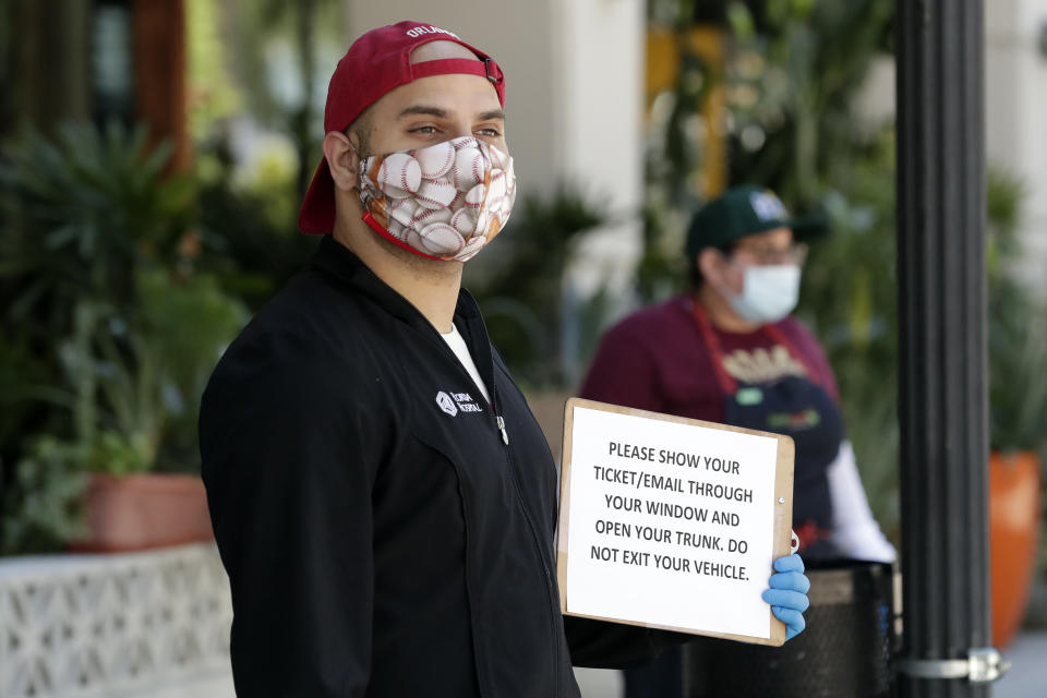 A volunteer worker holds a sign at a distribution point for residents that signed up online for free meals at a restaurant Wednesday, April 1, 2020, in Orlando, Fla. Workers from several restaurants helped give out fresh meals, part of a #ChefsForAmerica event, providing around 400 meals to residents today and tomorrow. (AP Photo/John Raoux)