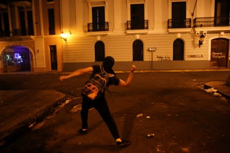 A demonstrator throws a stone at the police during clashes in a protest calling for the resignation of Governor Ricardo Rossello in San Juan