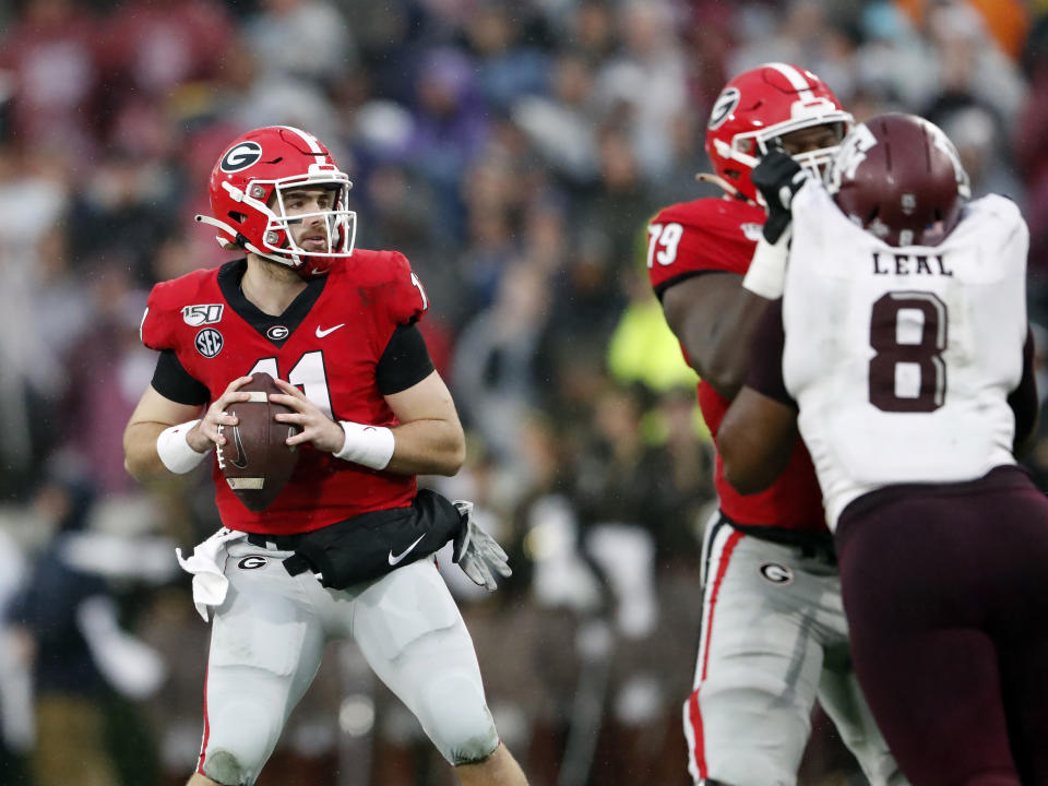 Georgia quarterback Jake Fromm (11) looks for a receiver as offensive lineman Isaiah Wilson (79) blocks Texas A&M defensive lineman DeMarvin Leal (8) in the first half of an NCAA college football game Saturday, Nov. 23, 2019, in Athens, Ga. (AP Photo/John Bazemore)