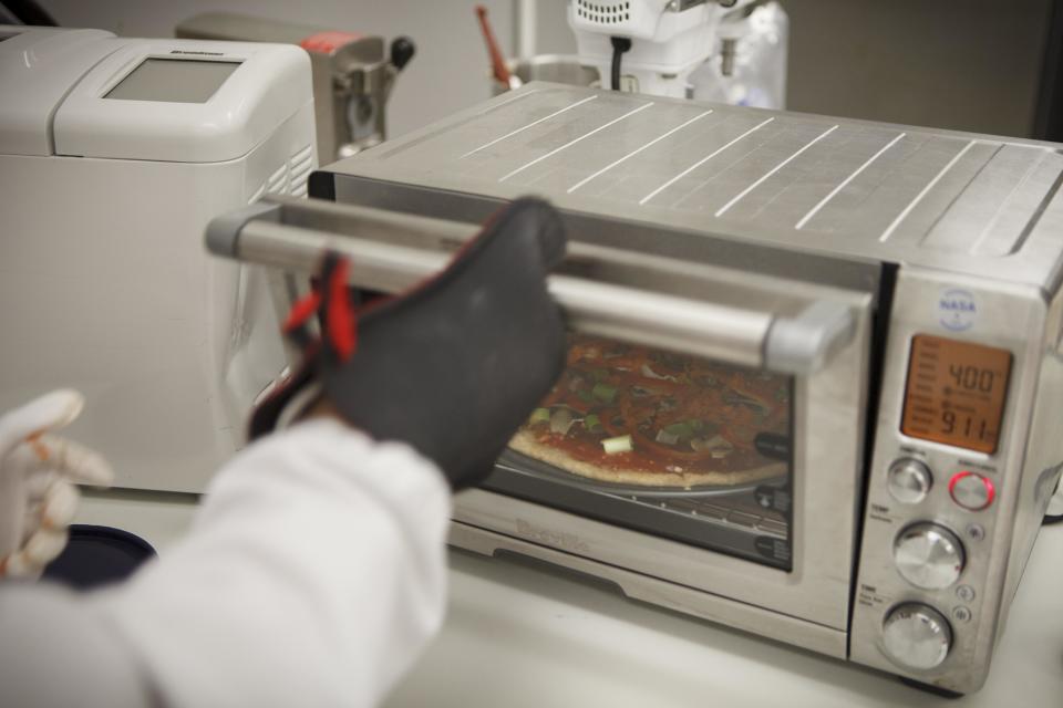 Lockheed Martin associate research scientist Monica Leong, bakes a vegan pizza from a recipe developed for a mission to Mars at NASA's Advanced Food Technology Project at Johnson Space Center in Houston Tuesday, July 3, 2012. NASA is currently planning a mission to Mars, which has gravity, so more options for food preparation, like chopping vegetables, are available as opposed to the dehydrated fare of current space missions. (AP Photo/Michael Stravato)