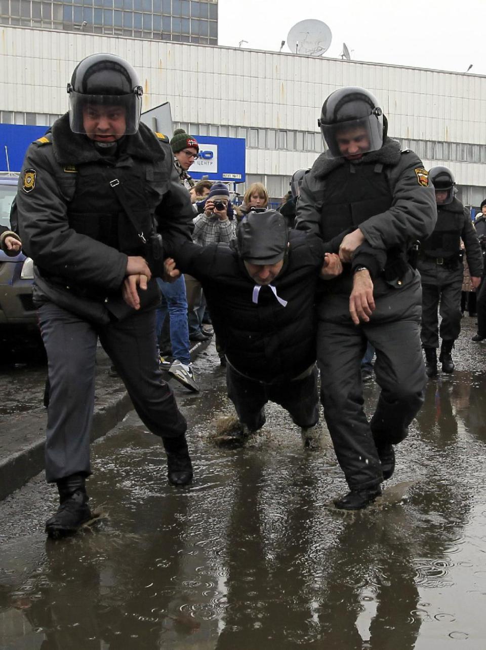In this Sunday, March 18, 2012 photo, police officers detain a protester outside the Kremlin-loyal NTV television station in Moscow. Russian opposition and human rights groups on Monday, Nov. 19, 2012, urged Western consumer products giants to stop "financing politically motivated persecution" by advertising on a Kremlin-friendly TV network known for its biased coverage of government critics and demonstrations against President Vladimir Putin. In the wake of unprecedented anti-Putin protests that followed last December's rigged parliament vote and Putin's return to the Kremlin in May, NTV has run dozens of news reports, talk shows and pseudo-documentaries accusing opposition leaders of plotting coups and terrorist attacks, of receiving money from Western governments, and of hiring migrant workers and neo-Nazis to participate in anti-Putin rallies. (AP Photo/Sergey Ponomarev)