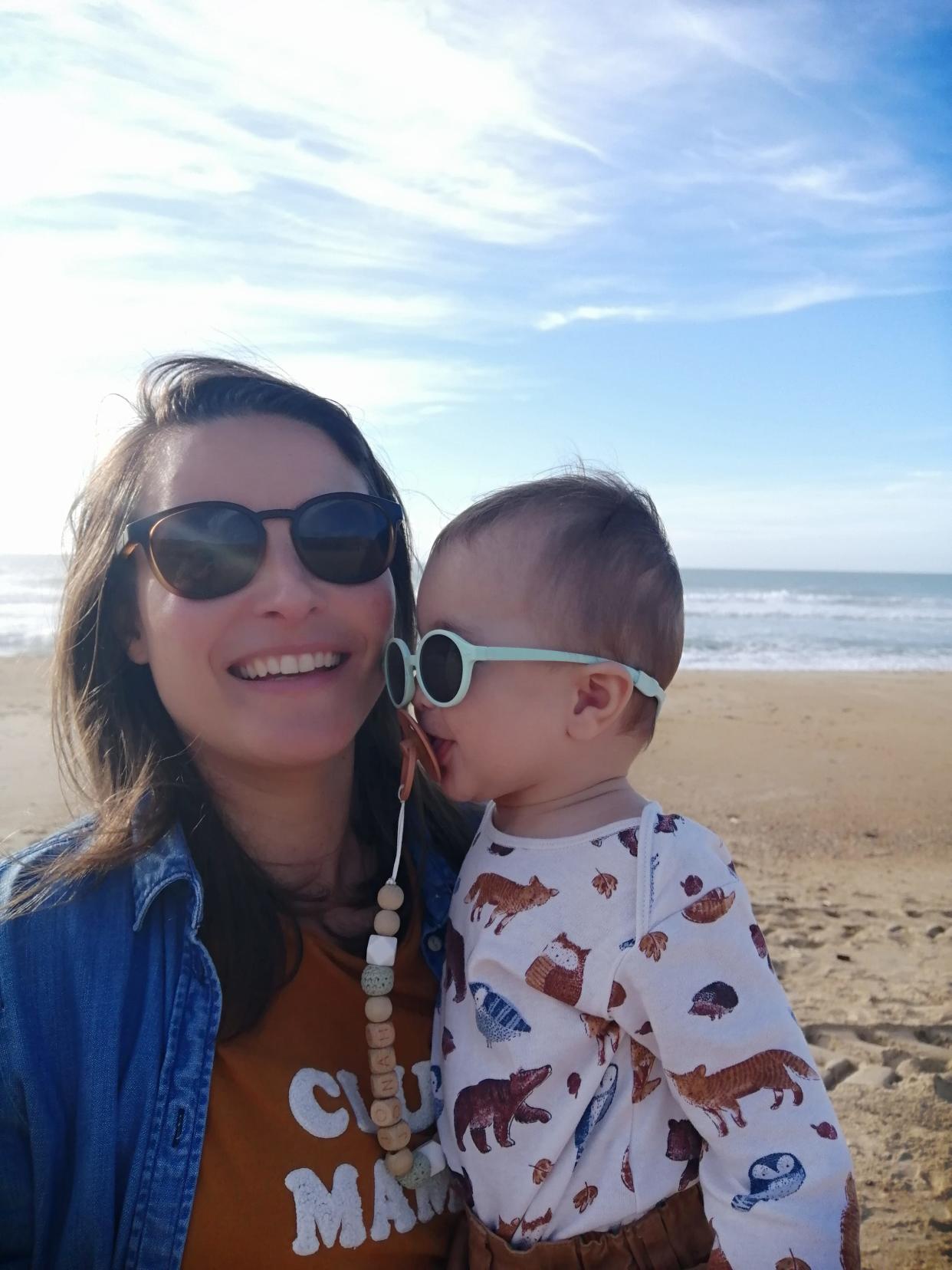 Anna's wife and their son, both wearing sunglasses on a beach