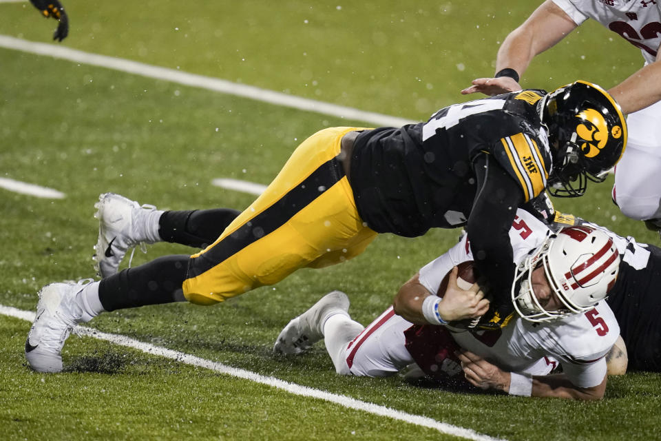 Wisconsin quarterback Graham Mertz (5) is tackled by Iowa defensive tackle Daviyon Nixon, left, during the second half of an NCAA college football game, Saturday, Dec. 12, 2020, in Iowa City, Iowa. Iowa won 28-7. (AP Photo/Charlie Neibergall)