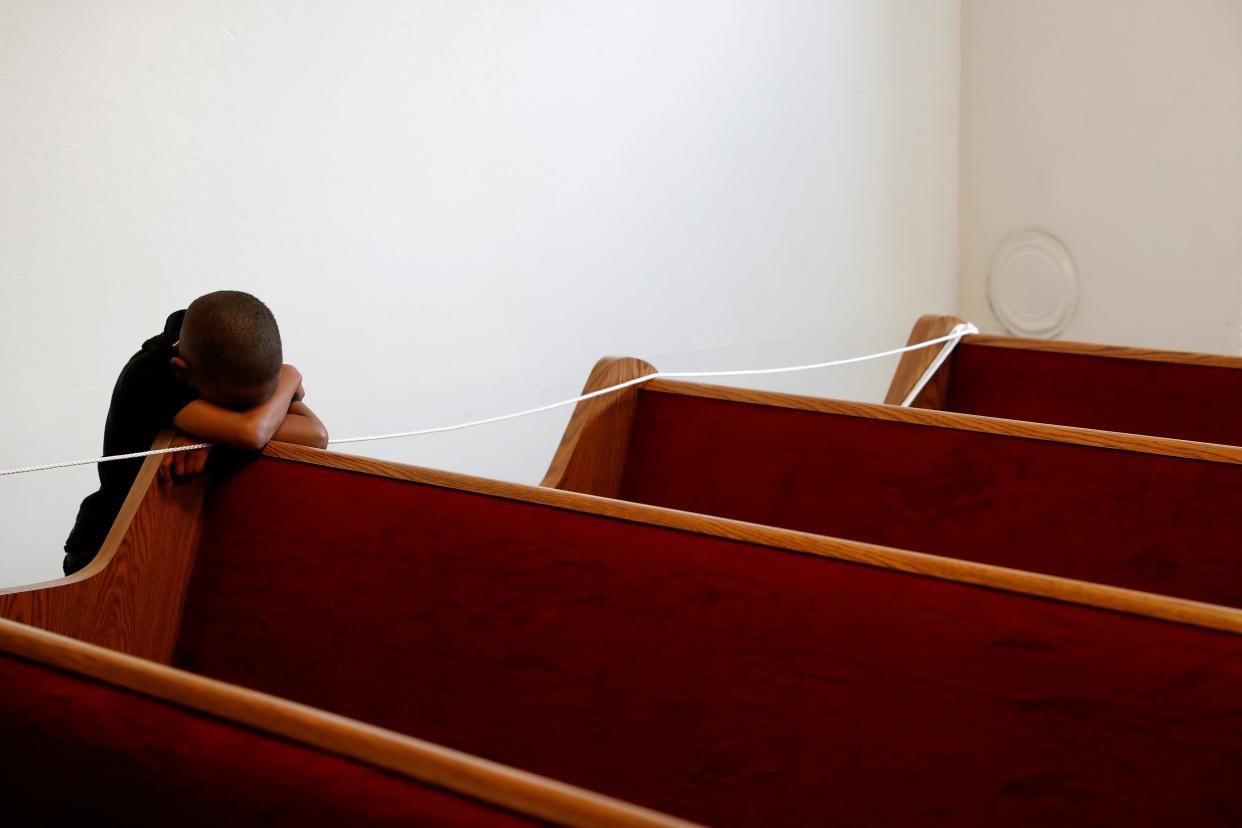 FILE PHOTO: Zechariah Payton, 5, puts his head down on an empty pew, on the third day of California Governor Gavin Newsom's implemented statewide "stay at home order" directing the state's residents to stay in their homes in the face of the fast-spreading coronavirus disease (COVID-19), before a Facebook Live service at Rising Star Church in Oakland, California, U.S. March 22, 2020. REUTERS/Shannon Stapleton/File Photo - RC2SXF9WEZC3