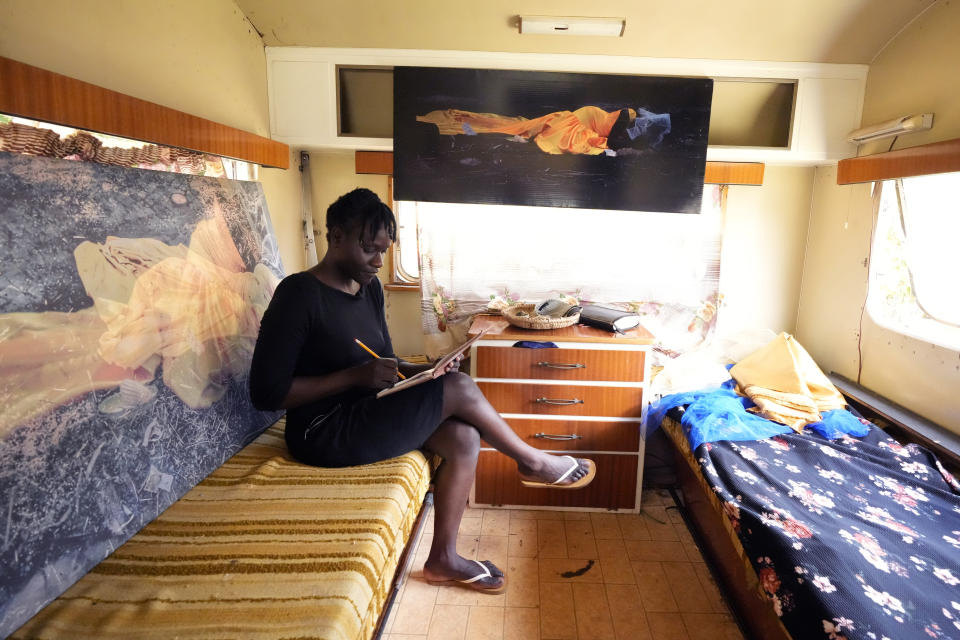 Zimbabwean artist Nothando Chiwanga jots down notes while seated in a caravan in the expansive yard of her family home in the suburbs of Harare, Friday, March 24, 2023. Chiwanga is one of 21 female artists whose works have been on show at the southern African country's national gallery since International Women's Day on March 8. The exhibition is titled "We Should All Be Human" and is a homage to women's ambitions and their victories, art curator Fadzai Muchemwa said. (AP Photo/Tsvangirayi Mukwazhi)