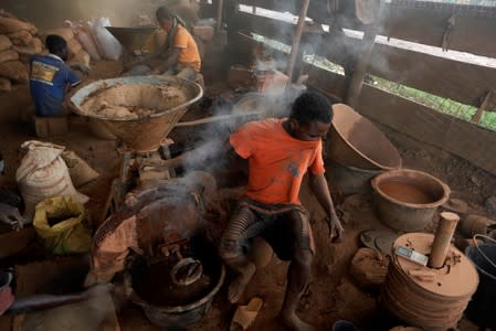 An informal gold miner uses his T-shirt to cover his face from the dust coming from a rock-breaking machine at the site of Nsuaem Top