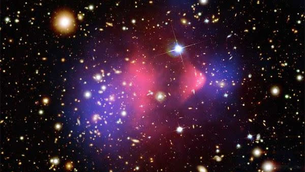 A composite image of the Bullet Cluster, a much-studied pair of galaxy clusters that have collided head on. One has passed through the other, like a bullet traveling through an apple, and is thought to show clear signs of dark matter (blue) separated from hot gases (pink). 