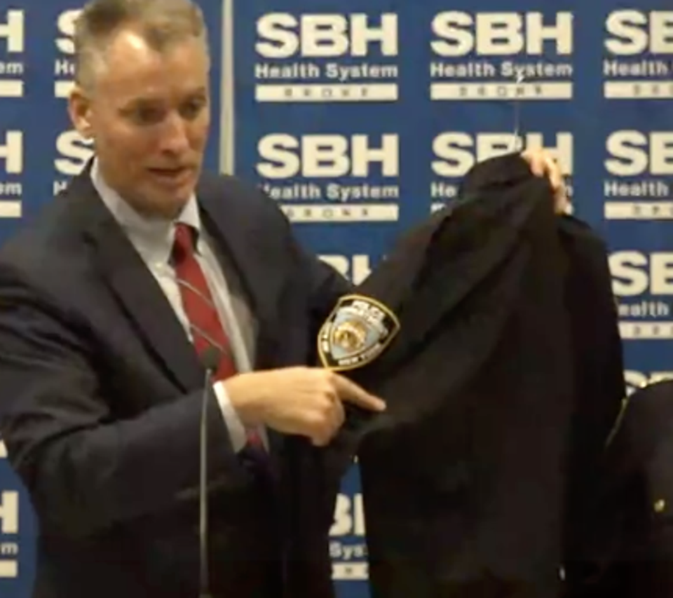 NYPD Commissioner Connor Shea points to where a hole pierced an injured police officer’s uniform (NYPD)