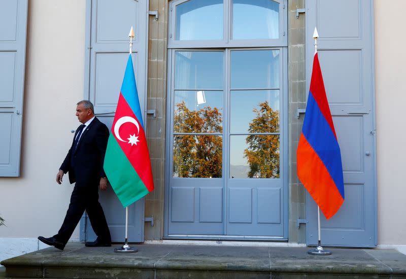 FILE PHOTO: A security guard walks past an Azerbaijan (L) and Armenian flag at the opening of talks in Geneva