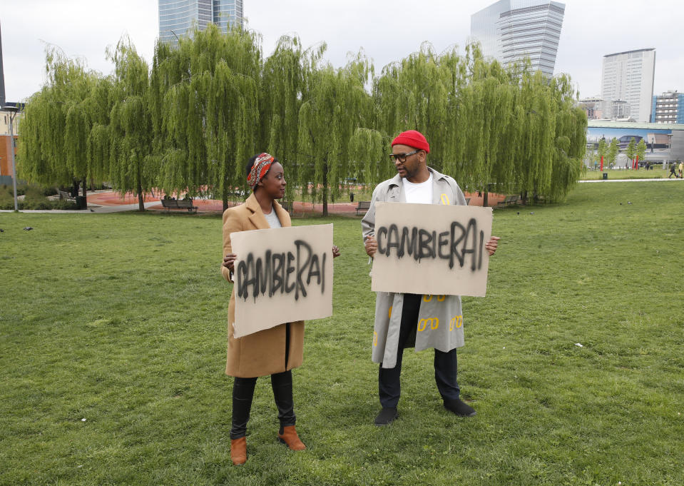 Sara Lemlem, left, and Jermay Gabriel Michael pose with banners reading in Italian "you will change" before an interview with the Associated Press, in Milan, Italy, Tuesday, April 27, 2021. The Netflix series “Zero,” which premiered globally last month, is the first Italian TV production to feature a predominantly black cast, a bright spot in an otherwise bleak television landscape where the persistent use of racist language and imagery in Italy is sparking new protests. (AP Photo/Antonio Calanni)