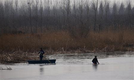 People catch fish at a partially frozen fish farm near an abandoned steel mill of Qingquan Steel Group in Qianying township, Hebei province February 18, 2014. REUTERS/Petar Kujundzic