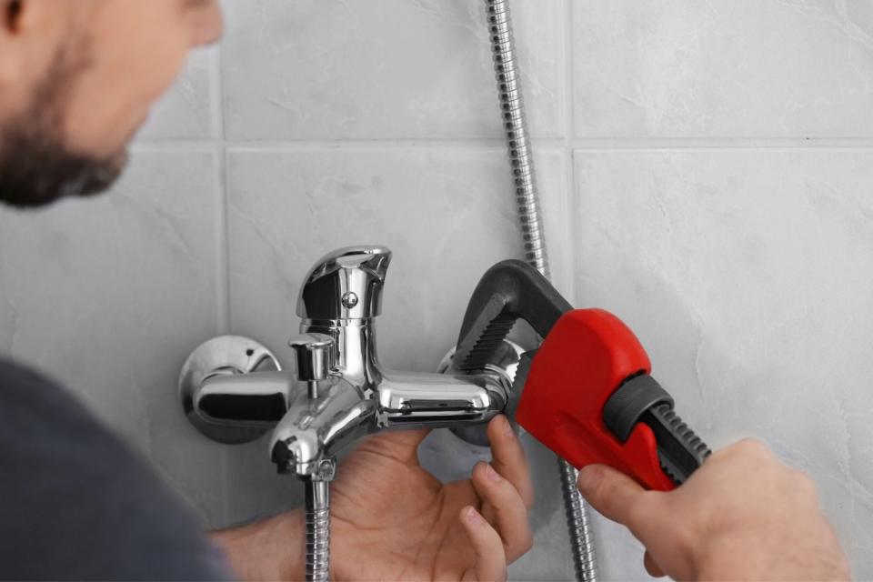 A close up of a man using a tool to fix plumbing.