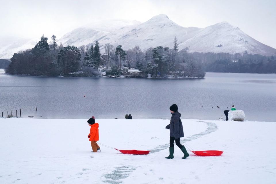 People pulling sledges in snowy conditions in Crow Park at Derwent Water near Keswick, Cumbria (PA)