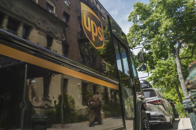 A UPS delivery driver wheeling a load of boxes is reflected on the truck on Friday, May 12, 2023, in New York. More than 340,000 unionized United Parcel Service employees, including drivers and warehouse workers, say they are prepared to strike if the company does not meet their demands before the end of the current contract on July 31. (AP Photo/Bebeto Matthews)