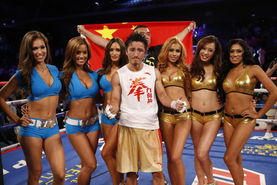 In this July 27, 2013 photo, Chinese boxer Zou Shiming, front center, poses with ring girls before the Flyweight bout match against Mexico's Jesus Ortega at the Cotai Arena in Venetian Macao in Macau. The Chinese fighter’s victory at a Macau showdown brings the world’s top casino market a step closer to challenging Las Vegas for dominance of another Sin City staple: big-time boxing matches. Macau, which long ago eclipsed Vegas as the world's top gambling city, is now looking to add to its allure by holding the kind of boxing bouts that Las Vegas is known for. (AP Photo/Dennis Ho)
