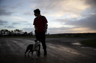 CORRECTS LAST NAME - Joe Watkins, 15, waits with his dog, Ellie, for the school bus near his home in Black River, Tasmania, Australia, Wednesday, July 24, 2019. Watkins’ mother was a dairy farmer when her drug addiction all began, a cheerful woman who loved taking Joe fishing and watching her daughter, Sarah, ride horses. And then one day, ten years ago, she jumped off a truck and felt her knees give way. (AP Photo/David Goldman)