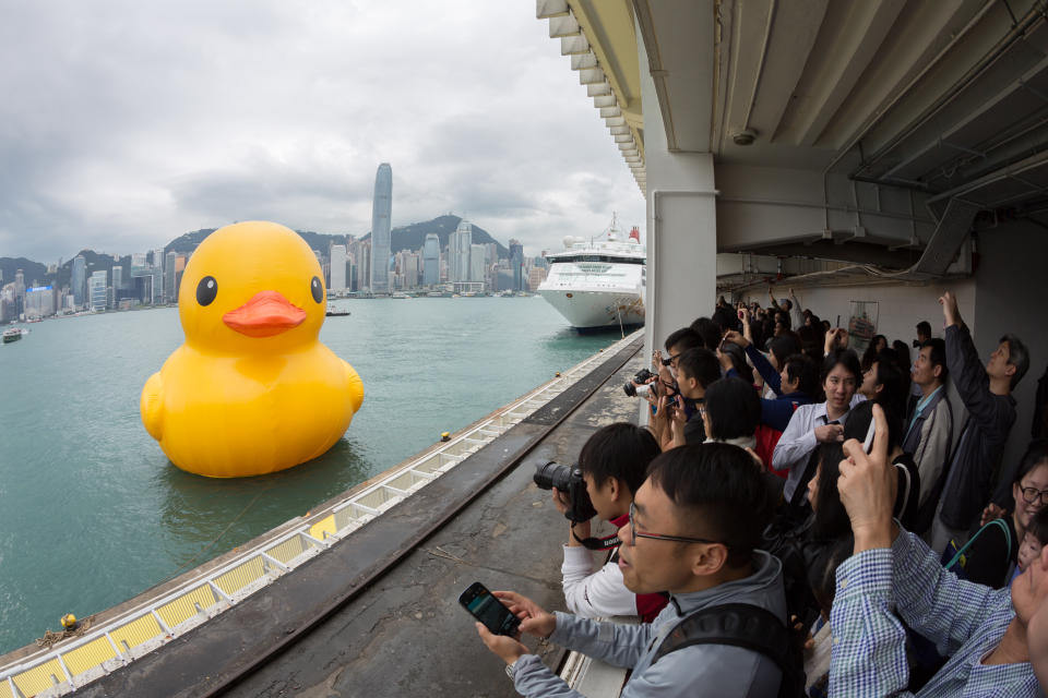 Hong Kong, China - May 2, 2013: People at Ocean Terminal, Tsim Sha Tsui, Kowloon, Hong Kong. Many people taking photo with the Rubber Duck. Rubber Duck has been travelling to 10 countries and 12 cities. Rubber Duck will be on display near Harbour City in Tsim Sha Tsui until June 9.