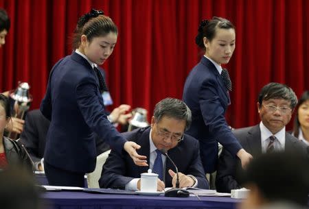 An attendant serves tea to Guangdong Communist Party Secretary Hu Chunhua as he attends the Guangdong delegation's group discussion during the National People's Congress (NPC) in Beijing, China March 6, 2013. REUTERS/Jason Lee