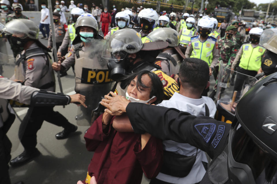 Supporters of Rizieq Shihab, leader of the Islam Defenders Front, scuffle with police officers during a rally in Jakarta, Indonesia, Friday, Dec. 18, 2020. Hundreds of protesters marched in Indonesia's capital on Friday to demand the release of the firebrand cleric who is in police custody on accusation of inciting people to breach pandemic restrictions and ignoring measures to curb the spread of COVID-19 by holding several events, and justice for his six followers who were killed in a shootout with the police. (AP Photo/Tatan Syuflana)