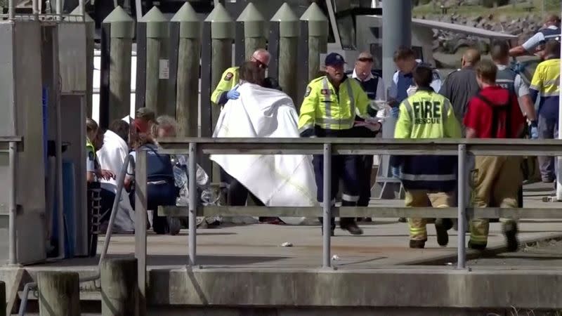 A person wrapped in a blanket is comforted by emergency services personnel following an eruption of the White Island volcano, in Whakatane