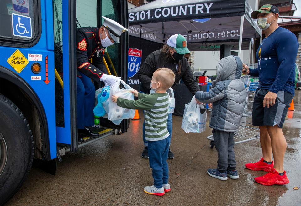 Marine Sgt. Robert Medina accepts a donation from Calvin Hammond as his brother Solomon Hammond hands off goods to FOOD for Lane County's Jennifer Ziegler-Monegan to help "Stuff the Bus" with their father, Nick Hammond, at Walmart on Nov. 13, 2020, in Springfield.