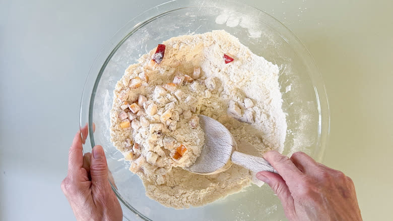 Stirring peaches into scone dry ingredients with wooden spoon