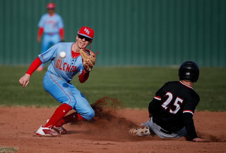 Glendale's Brooks Kettering catch a ball as McDonald County's Weston Gordon slides safely into second as the Flacons take on the Mustangs on Monday, March 20, 2023. 