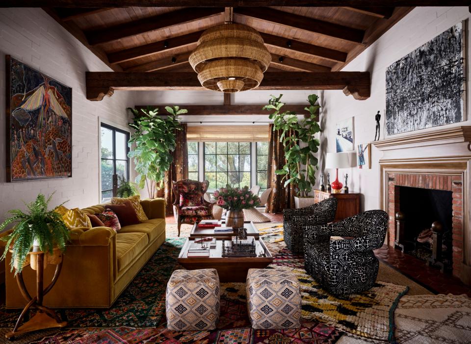 The voluminous living room is anchored by a collage of Moroccan rugs set atop a massive sisal carpet. The painting above the fireplace is by Hooper Dunbar. On the opposite wall is a painting by Frantz Zephirin.