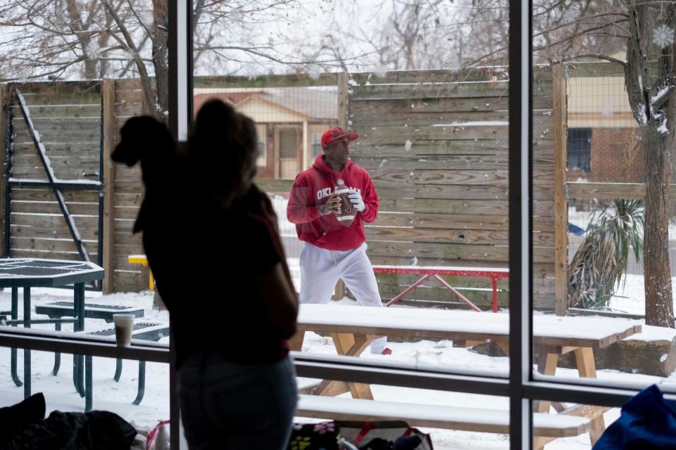 Austin Jordan-Windsor throws a football outside of the day shelter at the Homeless Alliance in Oklahoma City during a winter storm that moved across the area in December. Several shelters are offering additional beds to homeless residents this week as another storm moves through.