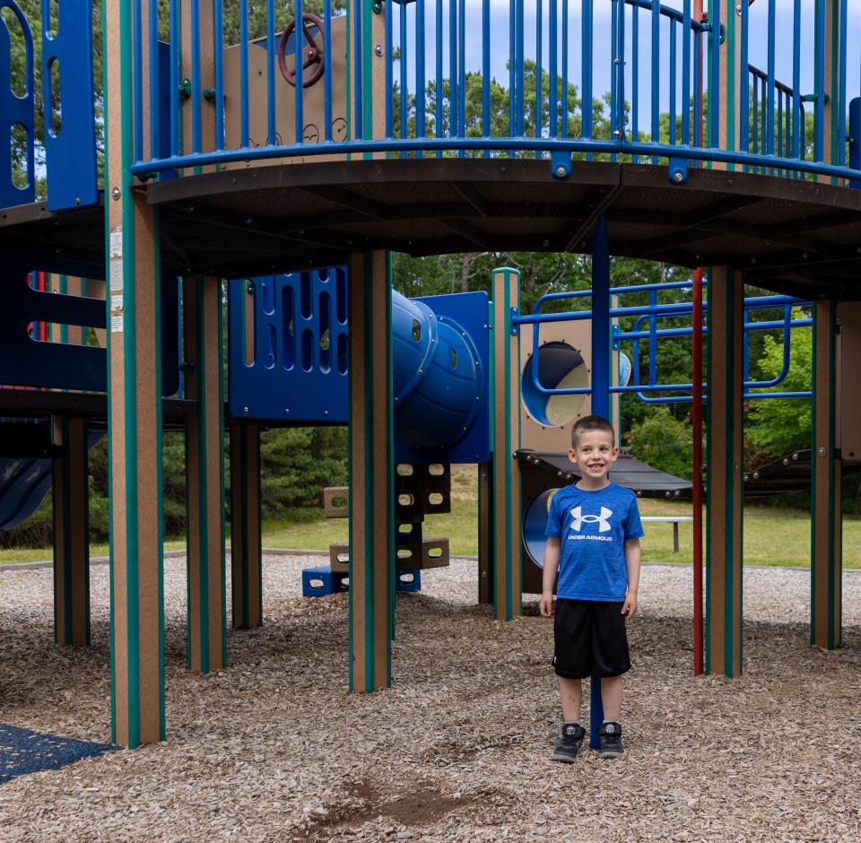 Pace Klida, 5, of Sandwich, stands in front of the pole to show how the height of the playground is too high.