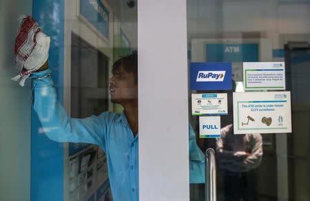 A RuPay sign is seen on the door of an automated teller machine (ATM) as a worker cleans it, at a commercial building in Mumbai September 11, 2014. REUTERS/Danish Siddiqui/Files