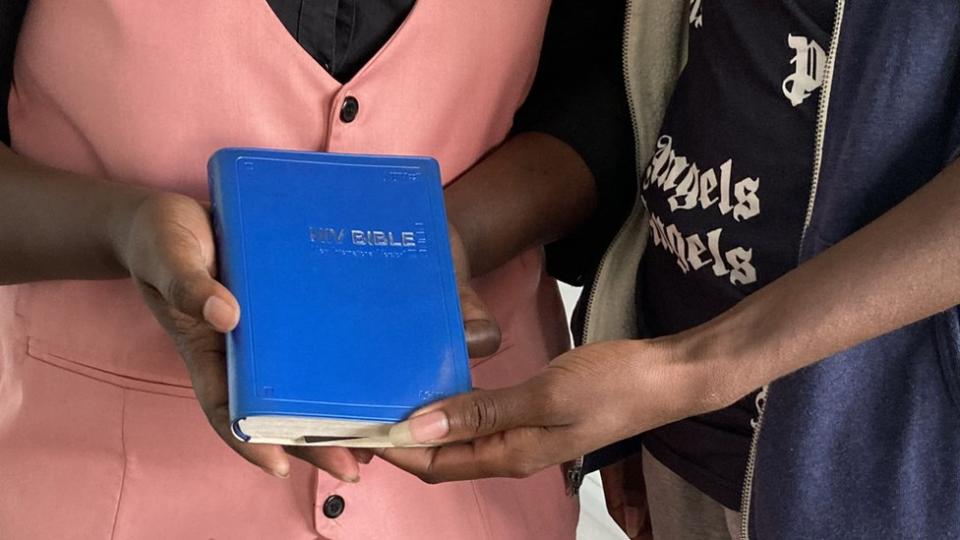 Two people at an LGBT -affirming church in Kenya holding a blue Bible
