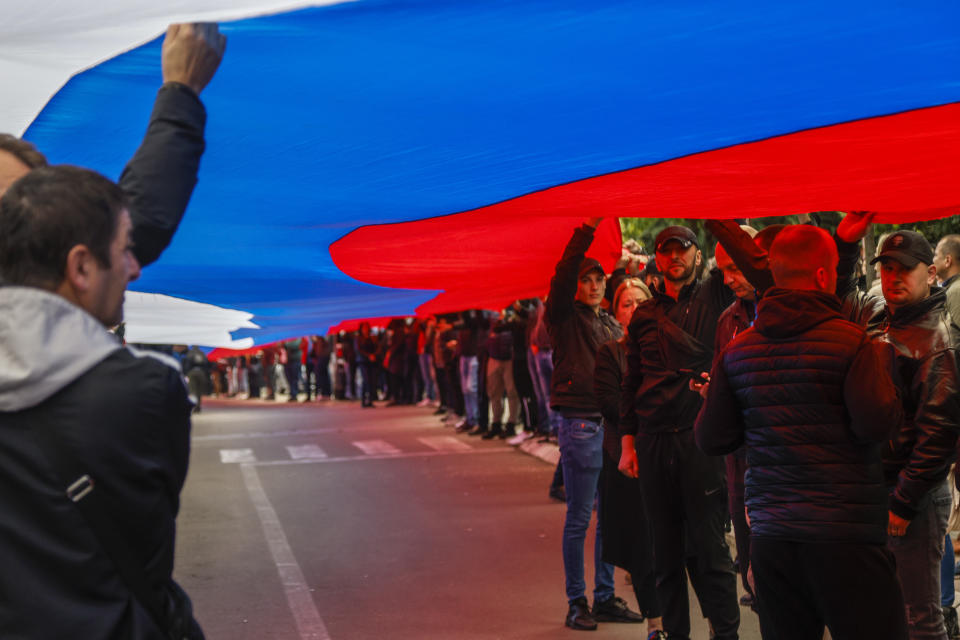 People hold a giant Serbian flag during a protest in front of the city hall in the town of Zvecan, northern Kosovo, Wednesday, May 31, 2023. Hundreds of ethnic Serbs began gathering in front of the city hall in their repeated efforts to take over the offices of one of the municipalities where ethnic Albanian mayors took up their posts last week. (AP Photo/Marjan Vucetic)
