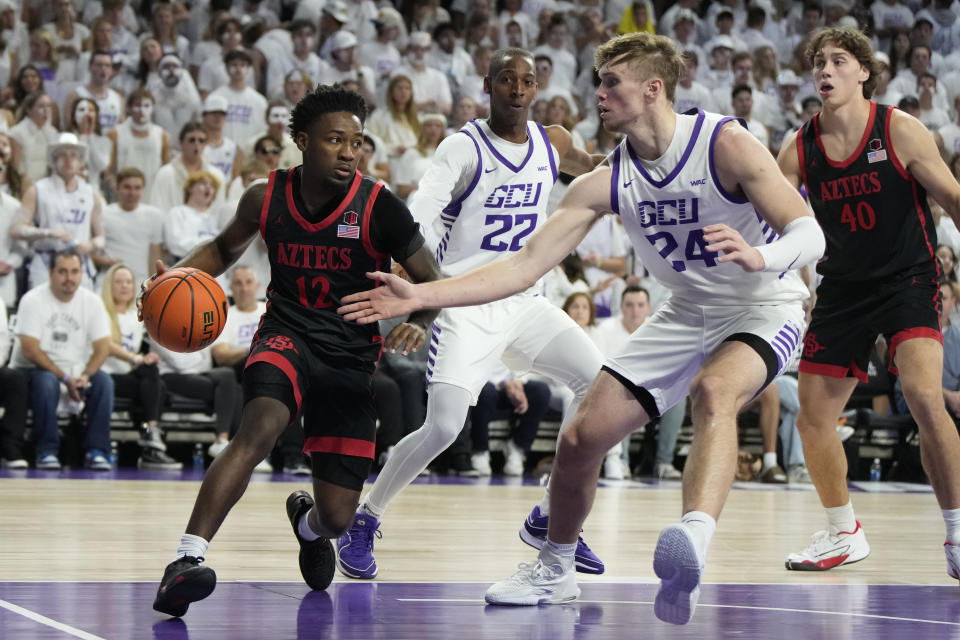 San Diego State guard Darrion Trammell (12) drives on Grand Canyon forward Duke Brennan (24) during the first half of an NCAA college basketball game Tuesday, Dec. 5, 2023, in Phoenix. (AP Photo/Rick Scuteri)