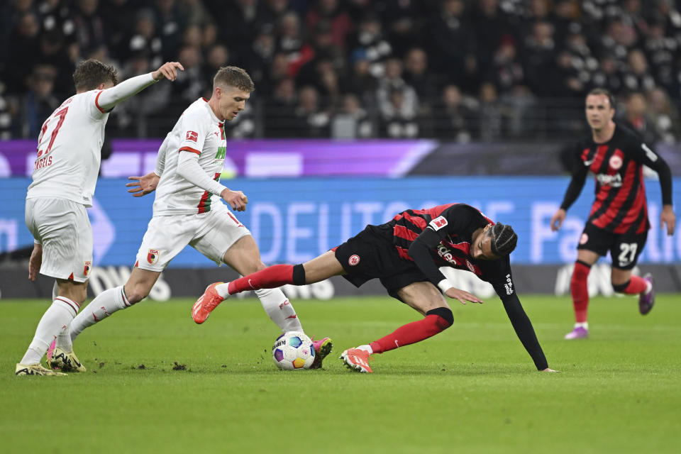 Frankfurt's Hugo Ekitike, right, and Augsburg's Kristijan Jakic and Arne Engels, left, battle for the ball during the German Bundesliga soccer match between Eintracht Frankfurt and FC Augsburg, in Frankfurt, Germany, Friday, April 19, 2024. (Arne Dedert/dpa via AP)