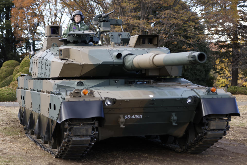 Japan's Prime Minister Fumio Kishida rides on a Japan Ground Self-Defense Force (JGSDF) Type 10 tank during a review at the JGSDF Camp Asaka in Tokyo, Japan, Saturday, Nov. 27, 2021. Kishida, at his first troop review Saturday, renewed his pledge to consider “all options,” including acquiring enemy base strike capability, and vowed to create a stronger Self-Defense Force to protect the country amid growing threats from China and North Korea. (Kiyoshi Ota/Pool Photo via AP)