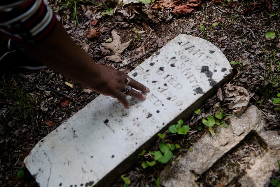 Olivia Metz inspects a recently cleaned headstone at the South Asheville Cemetery July 5, 2023.