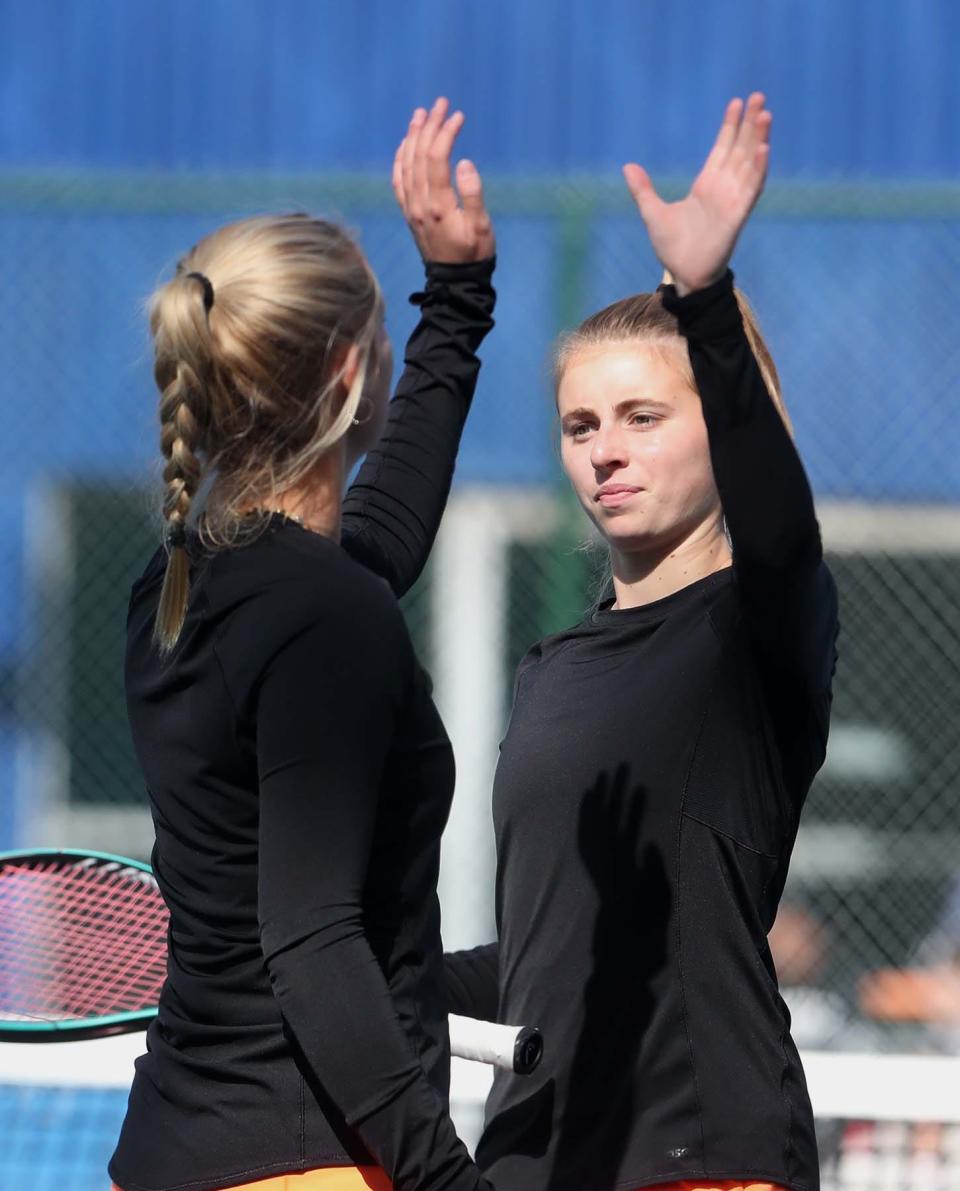 Cecilia Holben, left, of North Canton Hoover high-fives teammate Bridget Fink after they score a point against Addyson Utterback and Divya Shanmugan of Jackson during their battle for third place in doubles in the Division I district girls tennis tournament at Springside Athletic Club in Akron on Saturday.