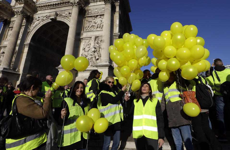 Demonstrators with yellow balloons and wearing their yellow vests demonstrate during a protest in front of the Arc de Triomphe of the Porte d'Aix, in Marseille, southern France, Saturday, Dec. 29, 2018. The yellow vest movement held several peaceful demonstrations in cities and towns around France, including about 1,500 people who marched through Marseille. (AP Photo/Claude Paris)